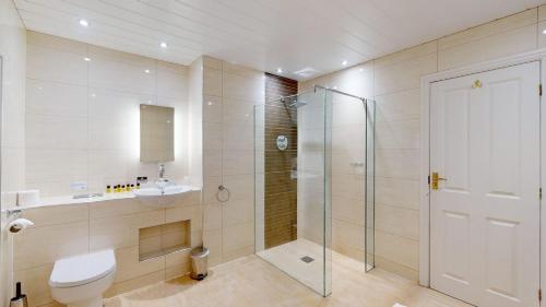 uma casa de banho com um chuveiro, um WC e um lavatório. em Stirk House Hotel em Clitheroe