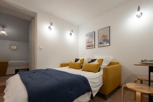 a bedroom with a bed and a yellow couch at Le Mimi Mosa - Parking public gratuit, wifi haut débit, proche autoroute, gare & centre ville in Mâcon