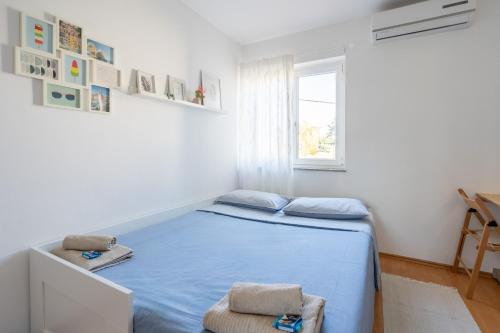 a bedroom with a blue bed and a window at Sunny & Cosy Studio wParking in Rovinj