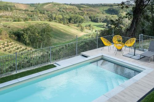 una piscina con 2 sillas amarillas y un balcón con vistas en Casa Verrua en Scurzolengo