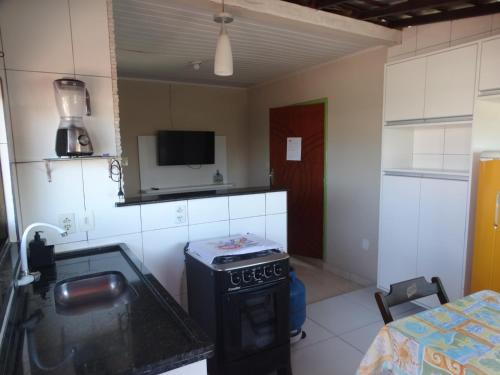 eine Küche mit einem Herd und einem Tisch im Zimmer in der Unterkunft Apartamentos da Coló in Arembepe