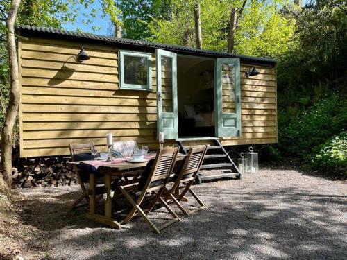 una mesa y sillas frente a una casa pequeña en Cosy Shepherds Hut Lyme Regis, en Uplyme