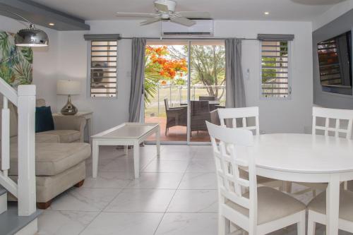 comedor y sala de estar con mesa blanca y sillas en 101H Jolly Harbour, Garden View, en Jolly Harbour