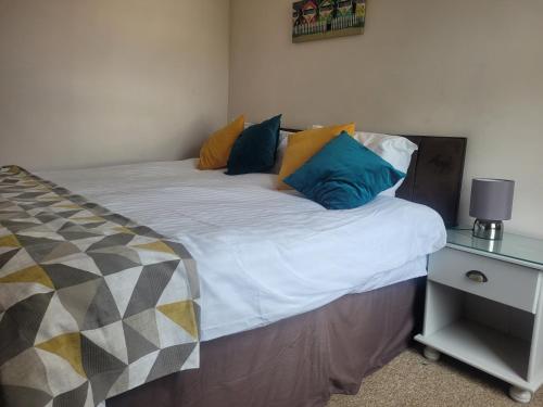 a bed with pillows on it with a night stand at Lovely 2 bedroom duplex apartment, Maidstone sleeps 5 in Maidstone
