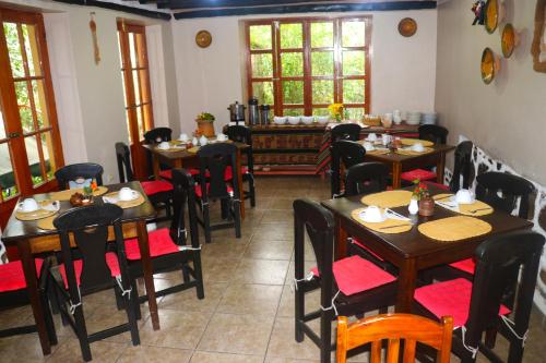 un comedor con mesas, sillas y ventanas en Wayras Hostal, en Ollantaytambo