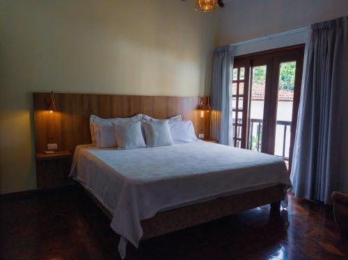 1 dormitorio con 1 cama con sábanas blancas y ventana en Hotel Boutique La Casa de Piedra, en Cali