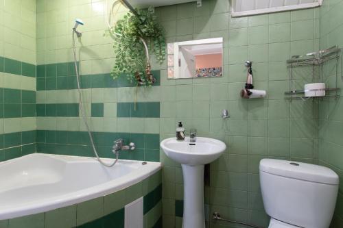 a green tiled bathroom with a sink and a toilet at Naykova district Apartments in Kharkiv