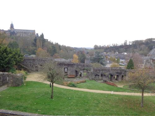 an old stone building with a green field and trees at Le Relais Médiéval in Fougères