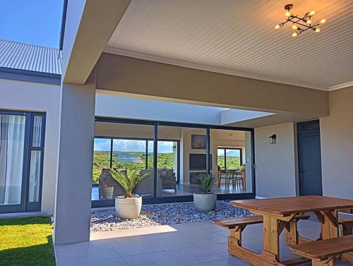 a patio with a wooden table and a wooden bench at Lighthouse Villa Romansbaai in Gansbaai