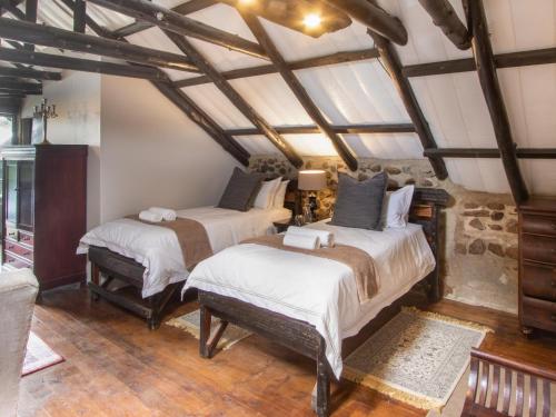 two beds in a room with wooden floors and ceilings at Flitwick Ranch in Swartberg