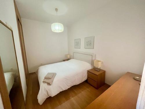 a small bedroom with a white bed and a table at Triana Marquesa in Melilla