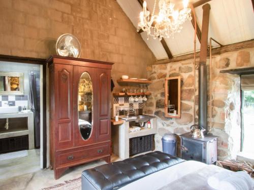 a bedroom with a large wooden cabinet in a stone wall at Flitwick Ranch in Swartberg