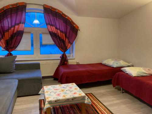 a living room with two beds and a window at Leśniczówka Pokoje Gościnne in Gdynia