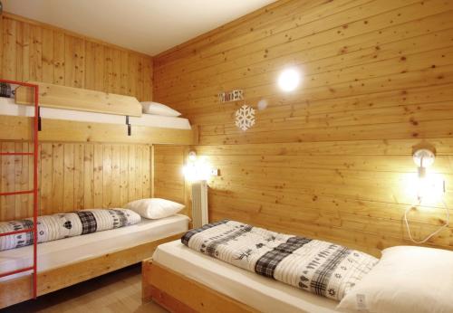 Ce lit se trouve dans un dortoir doté de 2 lits superposés et de murs en bois. dans l'établissement LA TANA - Residence Veronza con piscina, Dolomiti Affitti, à Cavalese