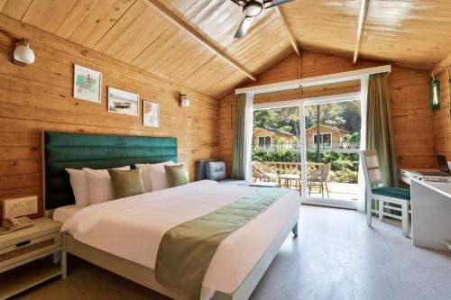 a bedroom with a large bed and a window at Stone Wood Jungle Resort, Dandeli in Dandeli