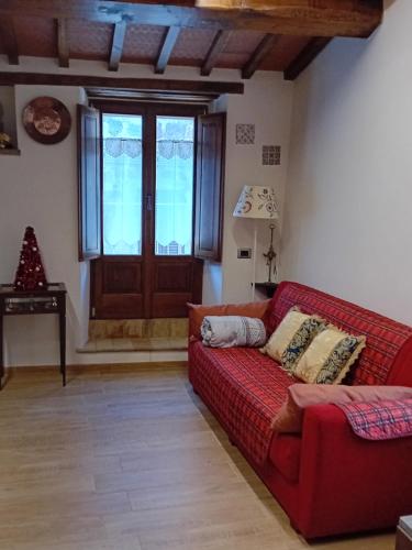 a living room with a red couch and a window at La Casa di Olga in Radicofani