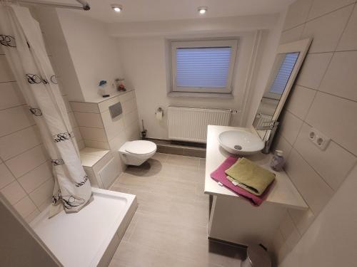 La salle de bains blanche est pourvue de toilettes et d'un lavabo. dans l'établissement Zimmer im Souterrain mit eigenem Bad, à Celle
