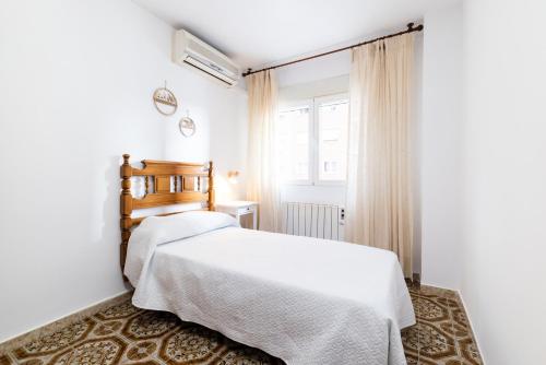 a bedroom with a white bed and a window at Piso junto a Parque de las Ciencias en Granada in Granada