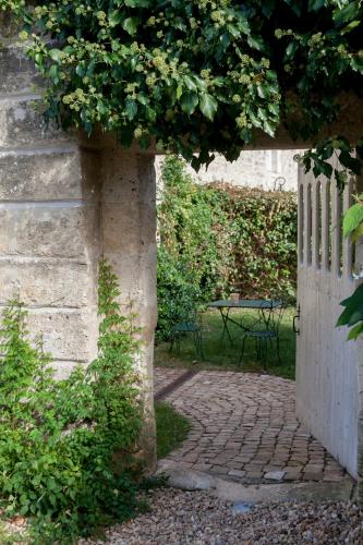 an open door to a garden with a brick walkway at Château Latour Segur Suites & Spa in Lussac