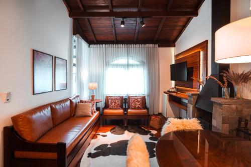 Vila Suzana Parque Hotel في كانيلا: غرفة معيشة مع أريكة جلدية وطاولة