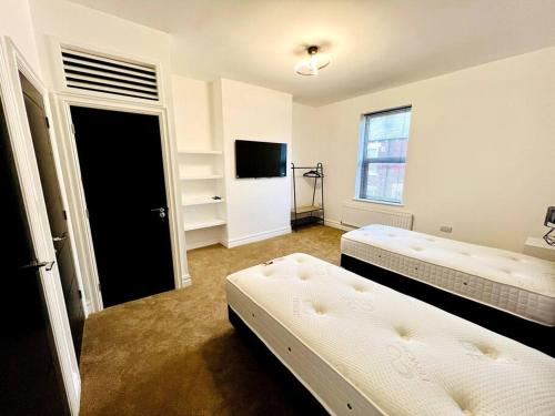 a room with two beds and a door with a television at Modern 2-bed in Blyth centre in Blythe