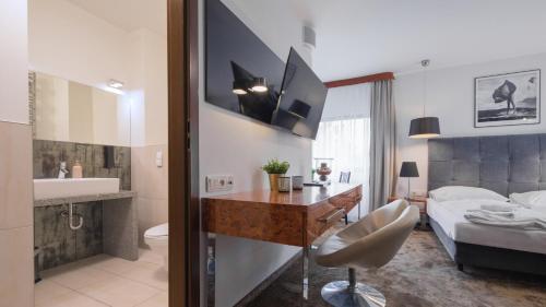 1 dormitorio con cama, escritorio y baño en VacationClub - Royal Tulip Sand Apartament 208, en Kołobrzeg
