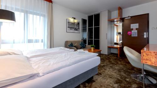 a hotel room with a large white bed and a chair at VacationClub - Royal Tulip Sand Apartament 208 in Kołobrzeg