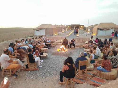 eine Gruppe von Menschen, die um ein Lagerfeuer sitzen in der Unterkunft agafay quad marrakech in Guertsdar