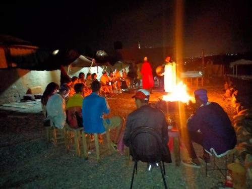 Eine Gruppe von Menschen, die nachts um ein Feuer herum sitzen in der Unterkunft agafay quad marrakech in Guertsdar