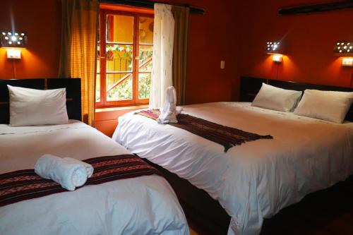una camera con due letti con lenzuola bianche e una finestra di Wayras Hostal a Ollantaytambo