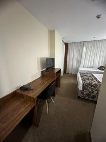 HOTEL condomínio EDIFÍCIO COMFORT TAGUATINGA FLAT في تاغاتينغا: غرفة في الفندق مع مكتب وسرير