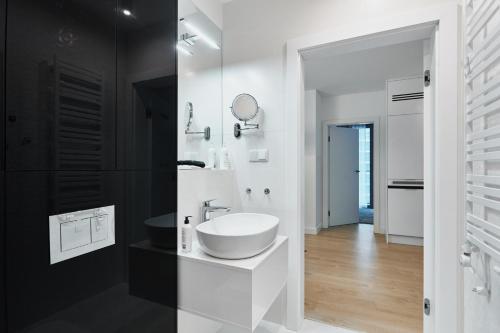 a white bathroom with a sink and a mirror at Wave Family Apartment - Sea View in Międzyzdroje