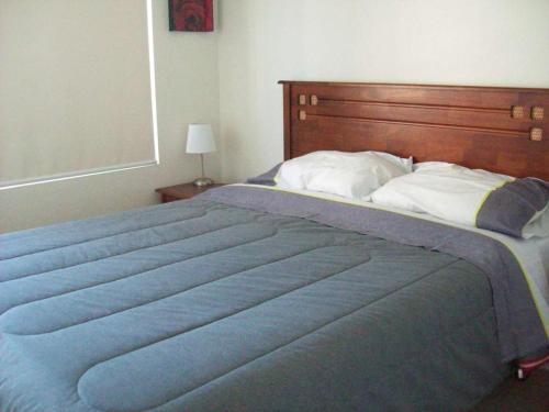 a large blue bed with a wooden headboard in a bedroom at Jardin del Mar in Coquimbo