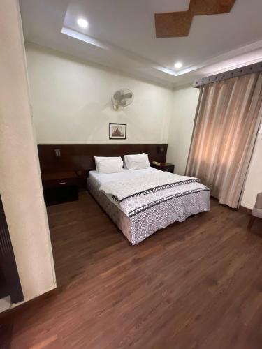 1 dormitorio con 1 cama grande y suelo de madera en Hotel Crescent, en Tahkāl Pāyān