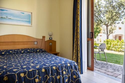 1 dormitorio con 1 cama y puerta corredera de cristal en Blu Salento Village, en Sant'Isidoro