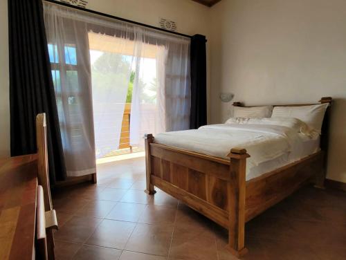 a bedroom with a bed and a large window at Babylon Lodge in Marangu