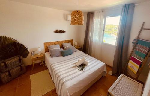 una camera da letto con un letto con lenzuola bianche e una finestra di L'amour à la plage...vue mer exceptionnelle ! a Les Trois-Îlets