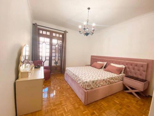 1 dormitorio con cama, mesa y lámpara de araña en GH Odivelas - Quartos em Casa com Bilhar!, 