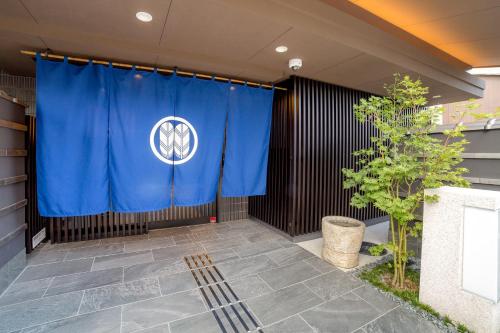 a blue curtain on a building with a tree at Kyoto Sanjo Ohashi in Kyoto