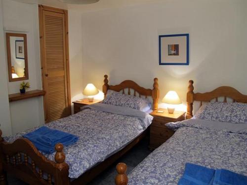 two beds in a bedroom with two lamps on tables at Fisherman's Cottage in Tobermory