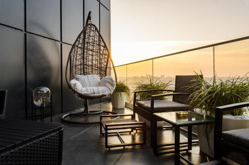 a balcony with a swing and chairs on a building at Q18 ApartHotel in Bydgoszcz