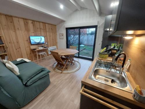 eine Küche und ein Wohnzimmer mit einem Waschbecken und einem Tisch in der Unterkunft La Cabane 14 in Lanton