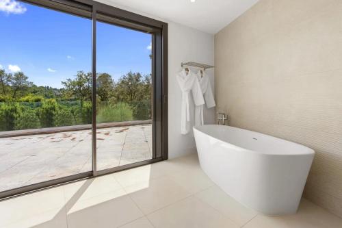 uma casa de banho branca com uma banheira e uma grande janela. em Grand Studio Valeriane em Trans-en-Provence