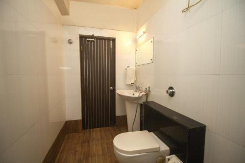 a white bathroom with a toilet and a sink at Hotel Sundaram Palace in Siliguri