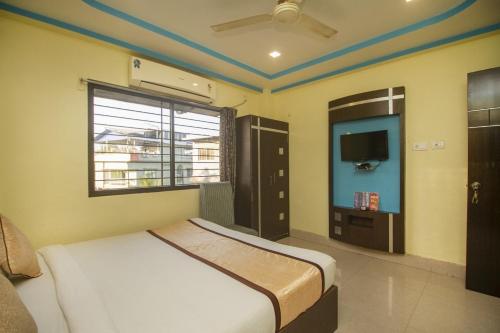 a bedroom with a bed and a flat screen tv at Hotel Sundaram Palace in Siliguri