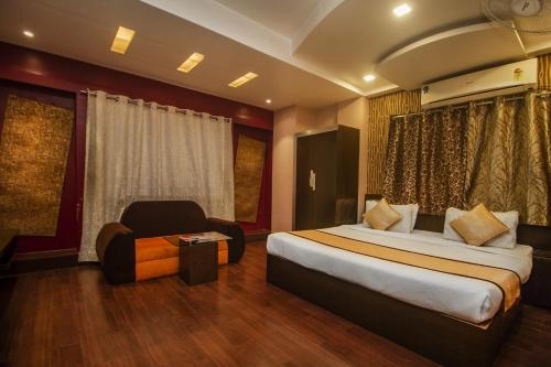 una camera d'albergo con letto e sedia di Hotel Sundaram Palace a Siliguri