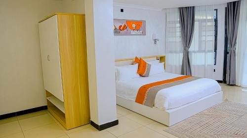 a bedroom with a white bed with orange pillows at The B Hotel in Kigali