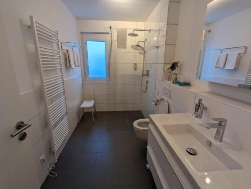 Baño blanco con lavabo y aseo en Golf & Wellness Suite Bad Bellingen Apartment 5-9, en Bad Bellingen