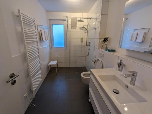 ein weißes Bad mit einem Waschbecken und einem WC in der Unterkunft Golf & Wellness Suite Bad Bellingen Apartment 5-9 in Bad Bellingen