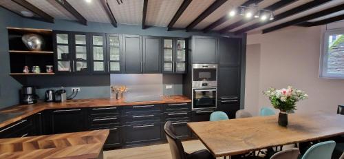 a kitchen with black cabinets and a wooden table at Bleautiful Joséphine - Maison de ville avec jardin in Fontainebleau